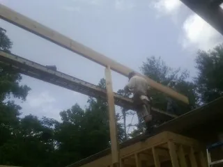 Carpenter setting a ridge beam over a new addition frame — Ice Dam Removal by Roofing Brothers in Saint Edward