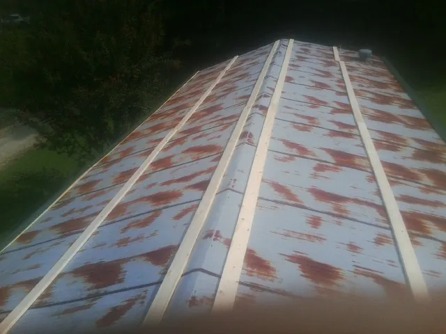 Rusted metal roof panels with new wood purlins before replacement — Storm Damage Roof Repair in Saint Edward by Roofing Brothers