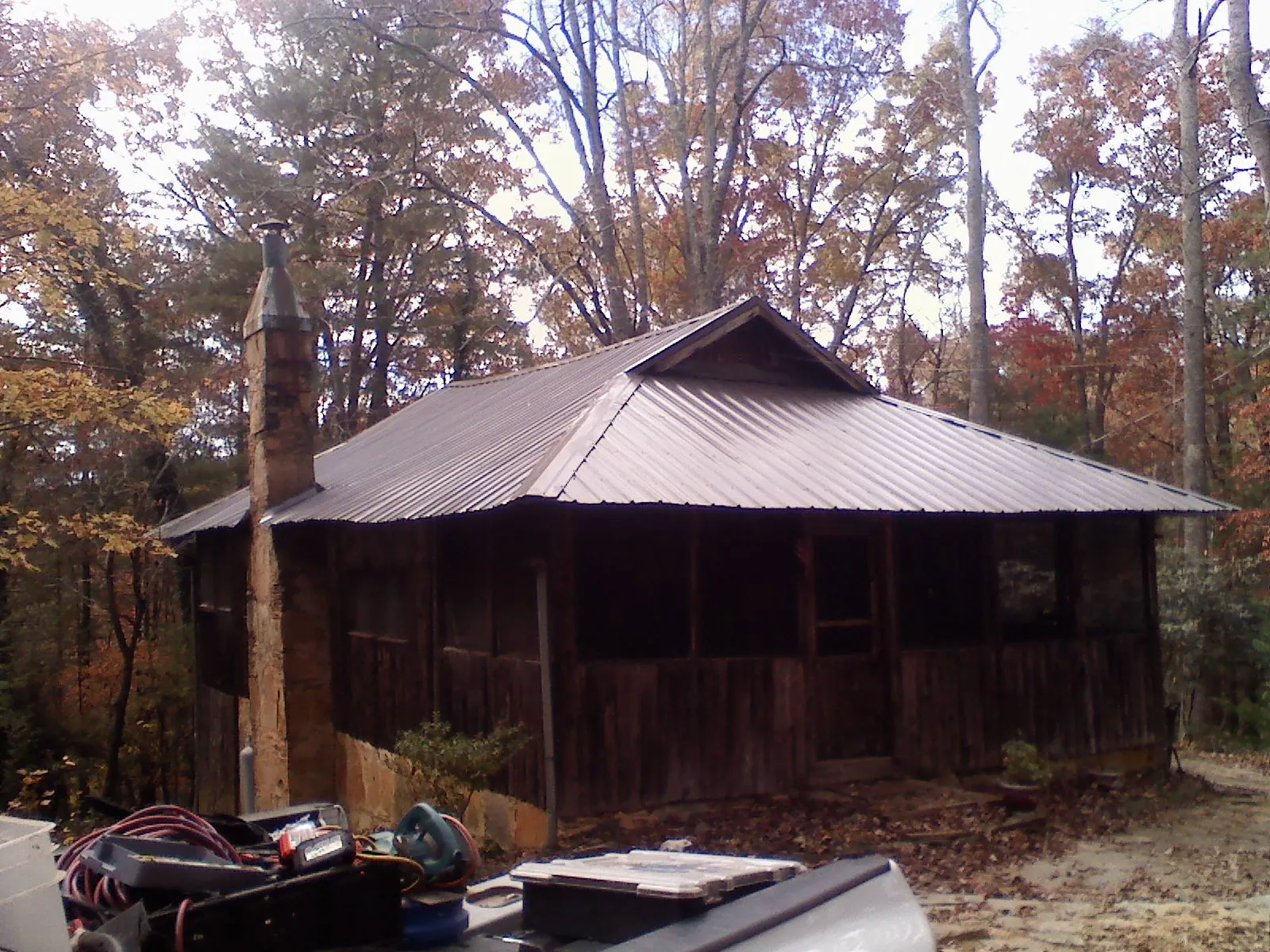 Brown metal hip roof on an old cabin with a stone chimney in Saint Edward