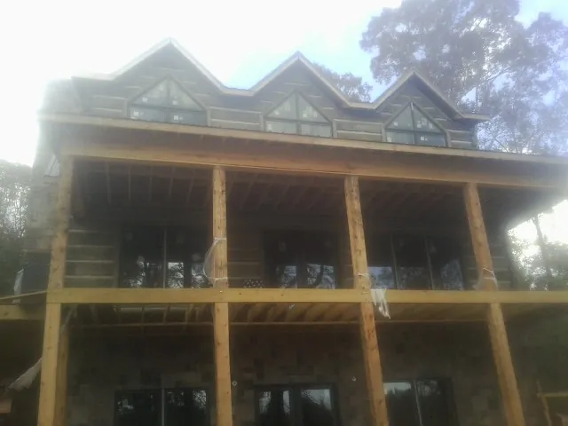 Dormers and porch framing on a large log home under construction — Roof Coating work by our crew in Saint Edward