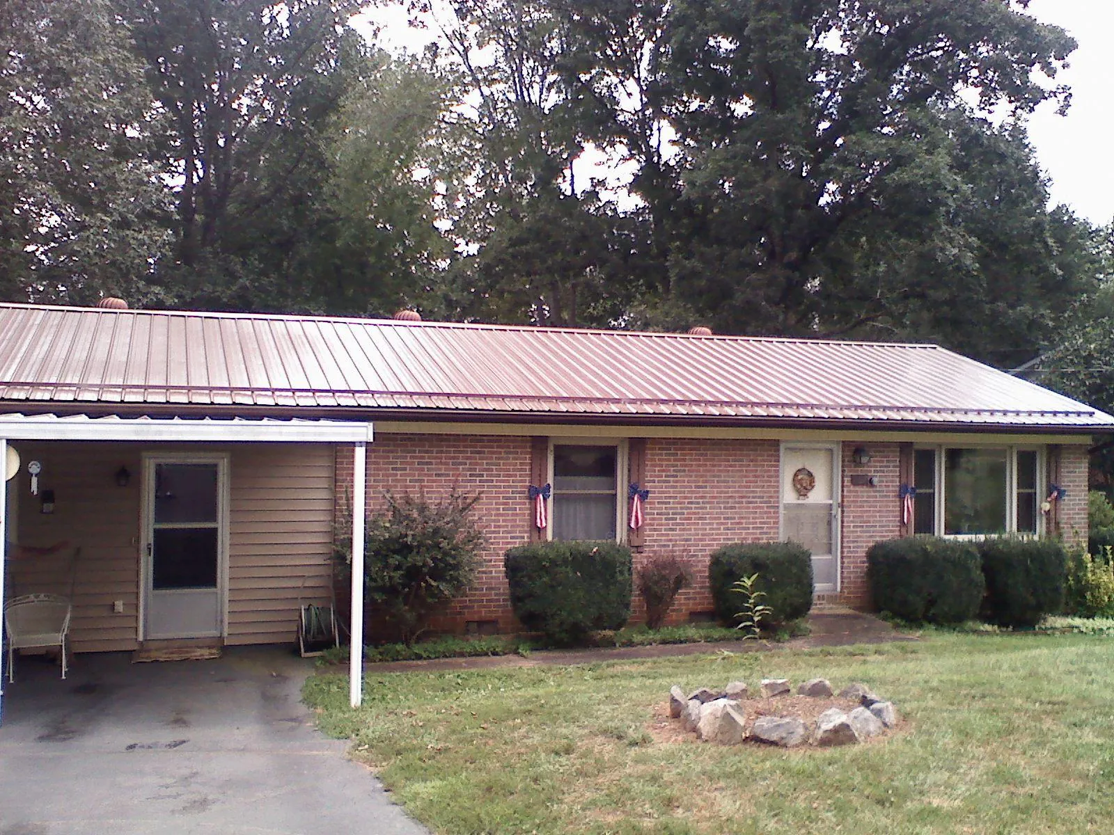 Bronze metal roof and carport on a brick ranch home — Roof Repair work by our crew in Saint Edward