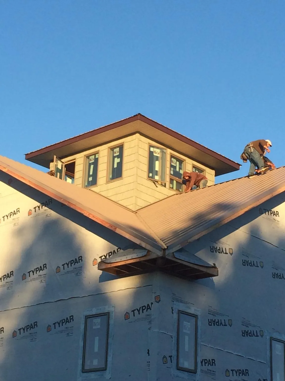 Roofers working around a rooftop cupola on a new metal roof at sunset — Roof Waterproofing in Saint Edward by Roofing Brothers